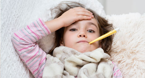 Little girl holding her head whilst having her temperature taken
